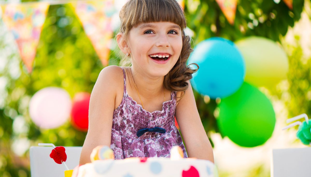 Happy pretty girl with cake at birthday party